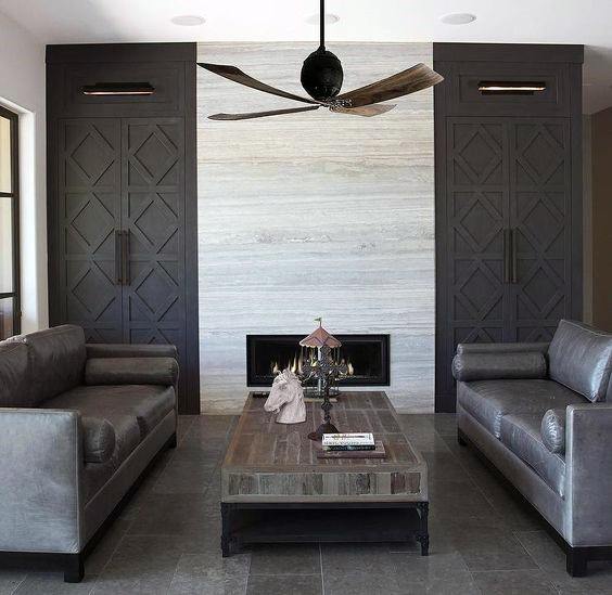 Luxury modern fireplace with sleek stone surround, dark cabinetry, and elegant decor.
