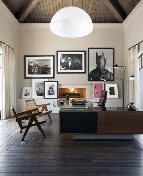 Stylish home office with gallery wall, glass desk, fireplace, and vaulted wood ceiling.