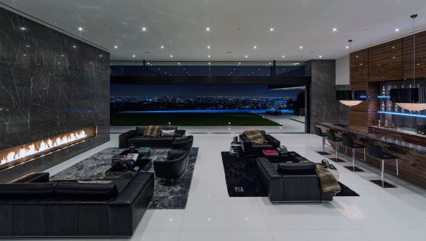 Luxurious modern living room with a fireplace, sleek black sofas, and expansive windows overlooking a cityscape at night