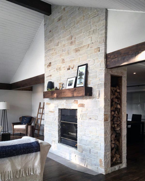 Living room with a natural stone fireplace, wooden mantel, and built-in wood storage.