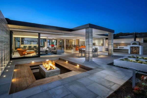 Modern patio with a fire pit, seating area, dining table, and mood lighting at dusk