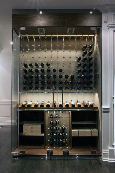 Elegantly arranged glass wine cellar with rows of wine bottles and wooden shelves, dimly lit for ambiance