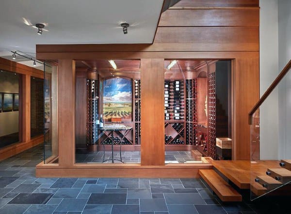 A modern wine cellar with wooden shelves, showcasing wine bottles, and a scenic vineyard mural on the back wall