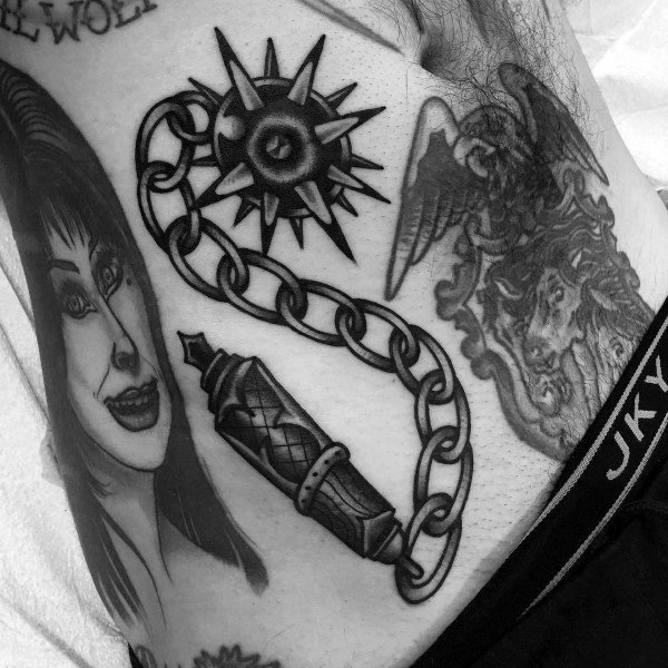 Black and gray mace tattoo with a spiked ball on a detailed chain, connected to a textured handle, symbolizing strength, battle, and resilience.