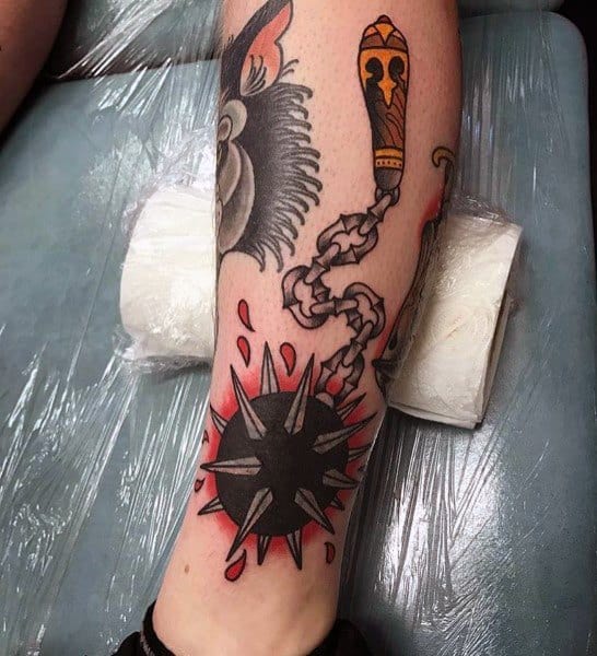 Bold mace tattoo with a spiked ball on a chain, featuring red accents and blood splashes, symbolizing power, battle, and medieval strength.