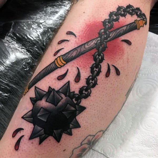 Bold mace tattoo with a spiked black ball on a chain, accented by red shading and blood drops, symbolizing power, battle, and resilience.