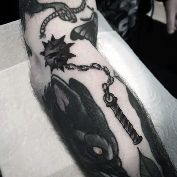Black and gray mace tattoo featuring a spiked ball on a chain with a textured handle, symbolizing strength, power, and medieval weaponry.