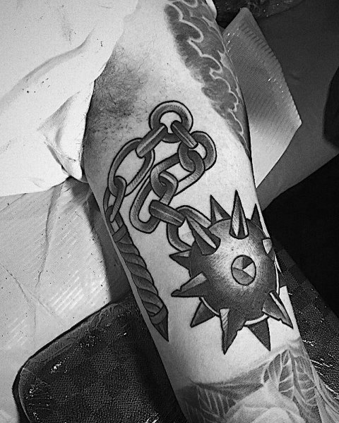 Black and gray mace tattoo featuring a spiked ball on a detailed chain with a textured handle, symbolizing power, battle, and resilience.