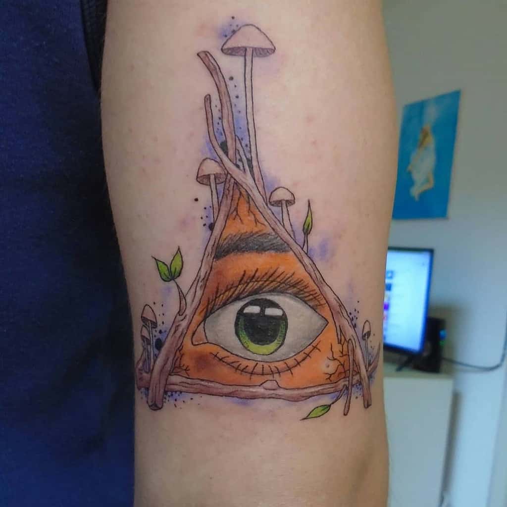 Tattoo of an all-seeing eye inside a triangular structure entwined with roots and mushrooms, inked in a watercolor style on the upper arm.