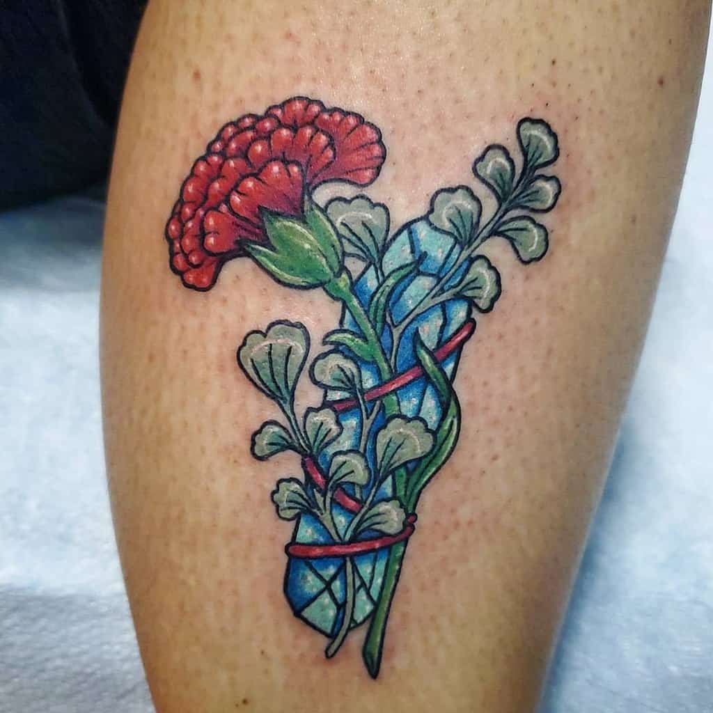 Tattoo of a red carnation with leaves, wrapped around a faceted blue crystal