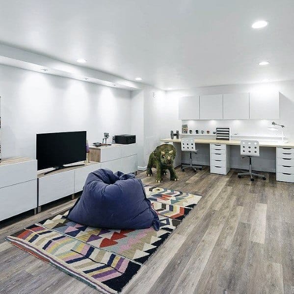Modern multipurpose room with bean bag, colorful rug, workspace, and sleek white cabinets.