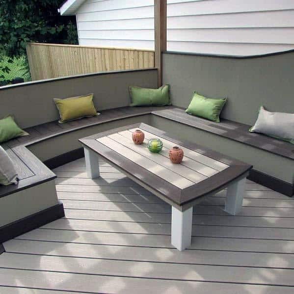 Curved bench with colorful cushions and a wooden table create a cozy outdoor seating area on the deck