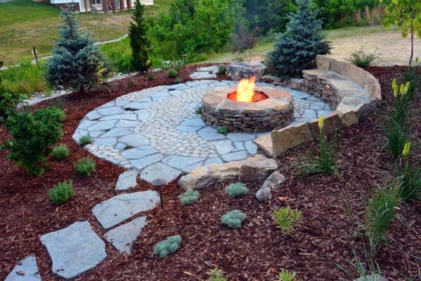 Stone fire pit with surrounding seating on a landscaped patio in a garden setting