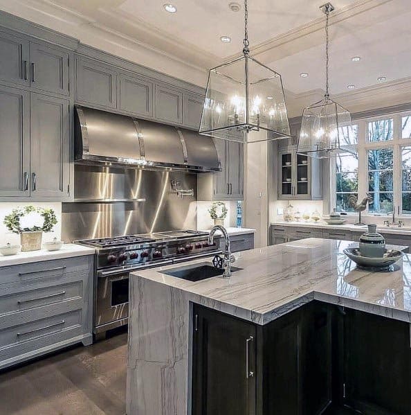 Grey kitchen with marble island, stainless steel range, and glass pendant lighting.