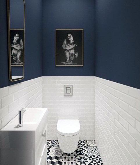 Navy blue half-bath with white brick tiles and bold patterned floor.