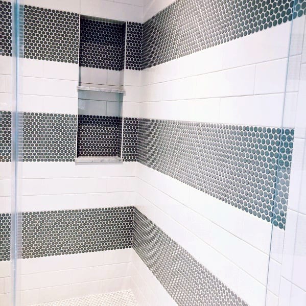 Shower with alternating white subway tiles and black penny tile stripes, featuring niches.