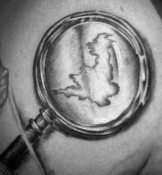 Tattoo of a magnifying glass focusing on a map of the United Kingdom, designed with realistic shading and intricate details for a bold look.