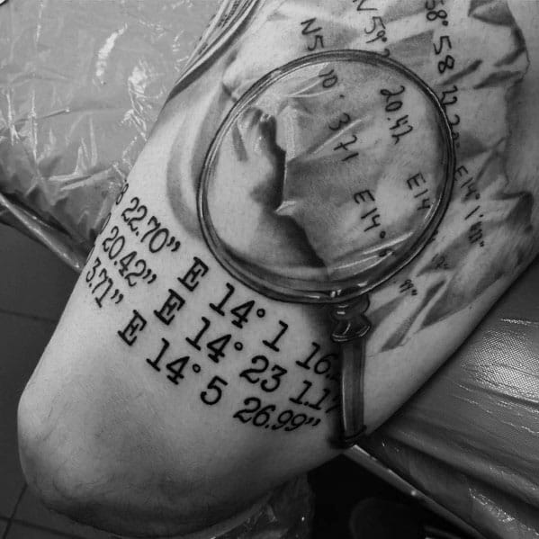 Tattoo of a magnifying glass focusing on coordinates, blending realism and symbolism with detailed shading for a unique and meaningful design.