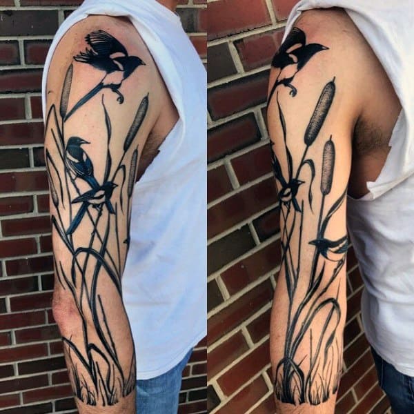 Black ink magpie tattoo sleeve featuring birds in flight among tall reeds and cattails, creating a natural and flowing design on the arm.