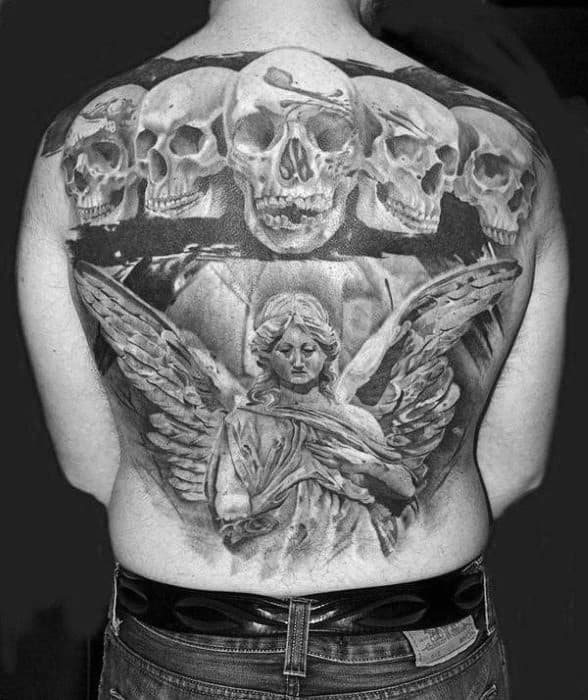 A large black and grey tattoo covering the back, featuring five skulls at the top and an angel in the center, surrounded by intricate details and shading.