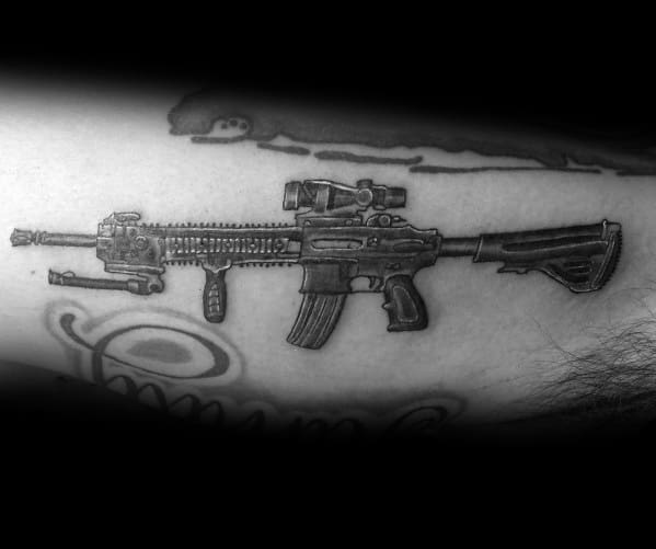 Black and grey AR-15 tattoo with a tactical scope and grip, featuring realistic shading and fine details, symbolizing strength, precision, and readiness.