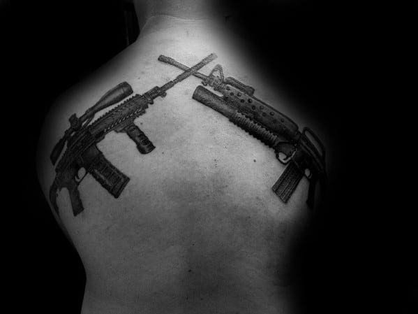 Black and grey back tattoo featuring two crossed rifles, symbolizing strength, tactical precision, and dedication to firearms or military service.