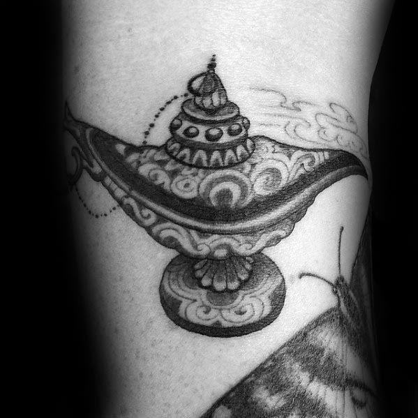Black and white tattoo of an ornate genie lamp on skin