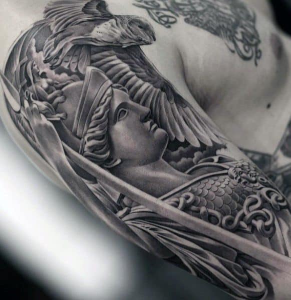Realistic Athena tattoo on upper arm with detailed armor, upward gaze, and owl in flight above, rendered in smooth black and grey shading