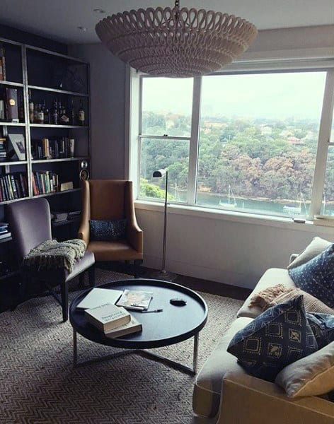 Cozy living room with bookshelf, comfortable seating, and large window with scenic view.