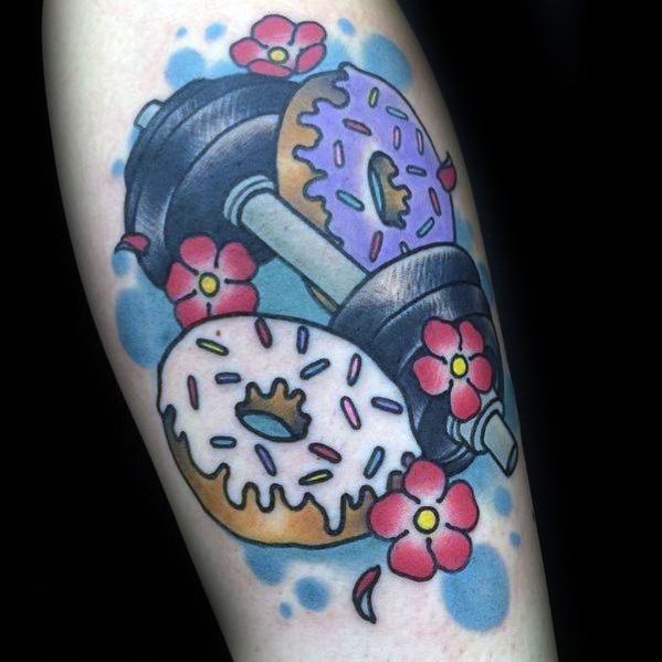 Colorful tattoo of a dumbbell with donut-shaped plates, flowers, and blue accents, blending fitness and fun with a playful twist.