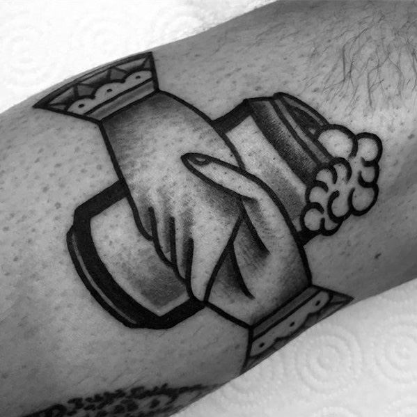 Bold blackwork tattoo of two hands shaking inside a beer mug, symbolizing friendship, unity, and shared moments over a drink.