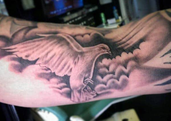 Black and grey tattoo of a majestic eagle soaring through clouds, with detailed feathers and soft shading for depth on the inner bicep