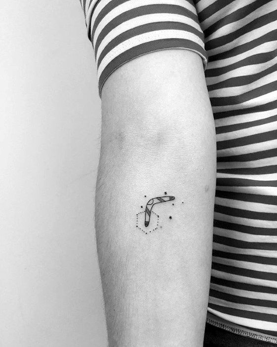Minimal boomerang tattoo on the forearm with a geometric constellation design made of fine dots and lines.