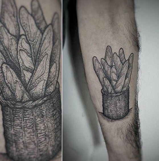 Black ink tattoo of multiple baguettes in a woven basket, featuring fine linework and shading for a rustic, artisanal bread-inspired design.
