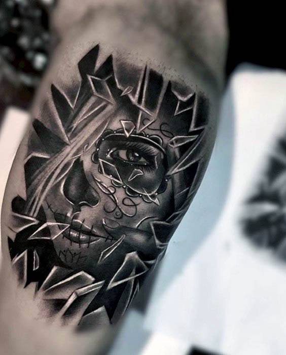 Surreal tattoo of a stitched face peering through shattered glass, with bold black shading and sharp fragmented edges for dramatic contrast.