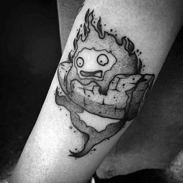 Black and grey Calcifer tattoo with dramatic shading, textured logs, swirling smoke, and a surprised expression on his face.