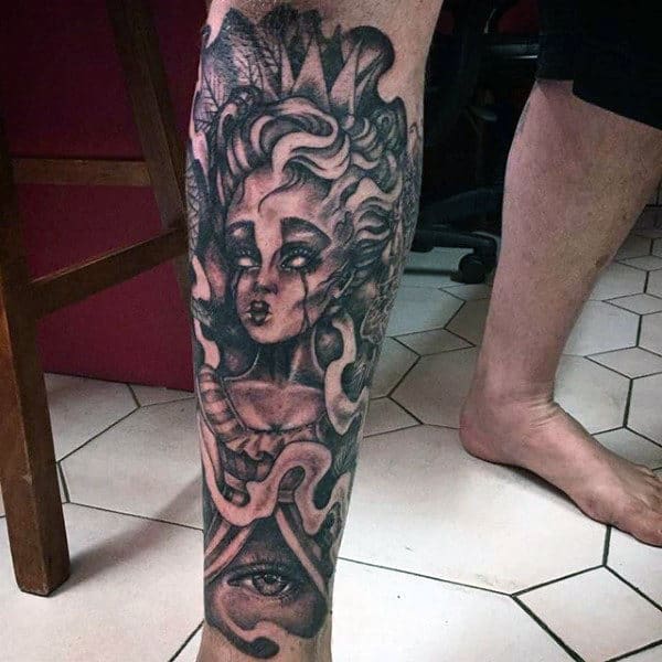 Dark, detailed calf tattoo of a mystical woman with flowing hair, snakes wrapped around her, and an all-seeing eye below