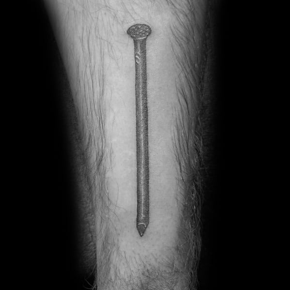 Realistic black and gray tattoo of a single nail on the forearm, symbolizing strength, resilience, and dedication to craftsmanship.