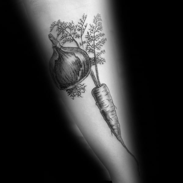 Black and gray tattoo of a carrot and onion on the forearm, featuring fine line detailing and realistic shading for a bold botanical design.
