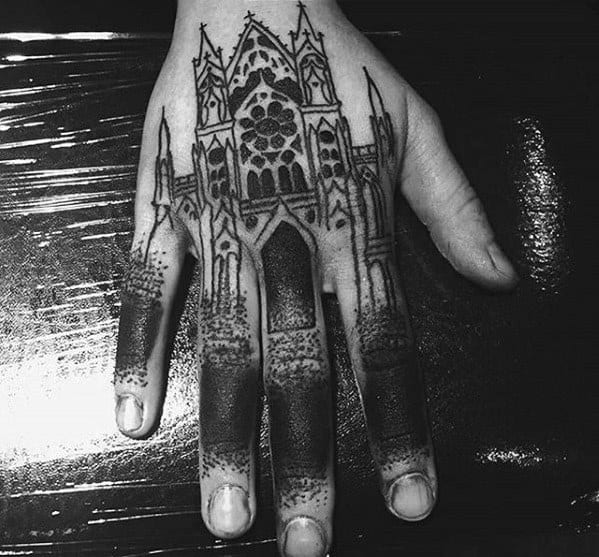 Hand tattoo of a gothic cathedral spanning across fingers and back of the hand, with dotwork shading and detailed spires and arches.