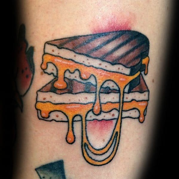 Colorful tattoo of a grilled cheese sandwich with melted cheese dripping, featuring bold black outlines, vibrant yellow-orange shading, and detailed grill marks.