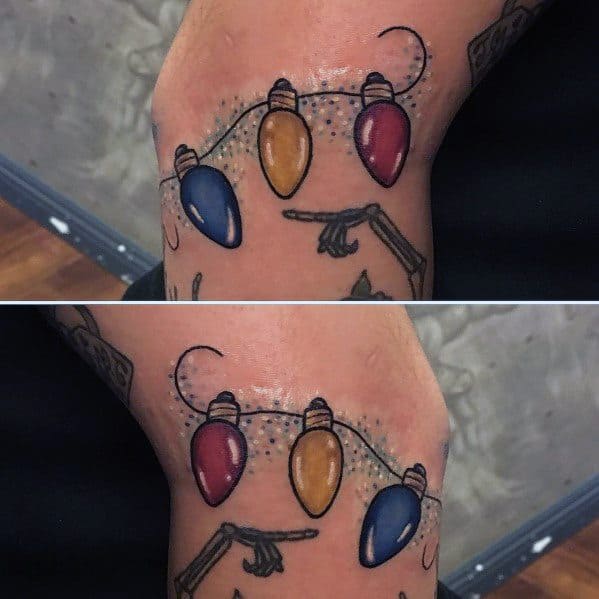 Christmas tattoo of colorful holiday lights strung across the elbow, incorporating a clever design that moves with the joint for a dynamic festive effect.