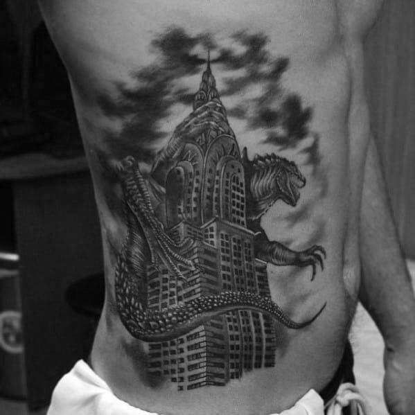 Black and grey tattoo of the Chrysler Building with a monster wrapped around it, detailed shading for a bold look on the ribcage.