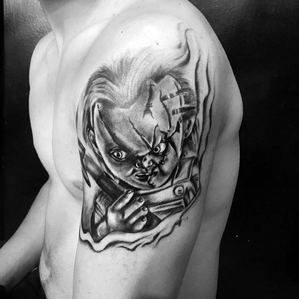 Black and grey Chucky tattoo with intense shading, featuring his stitched face, piercing eyes, and a knife for a bold horror-inspired design.