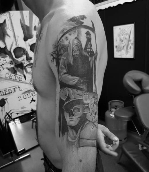 Black and grey arm tattoo of the Grim Reaper holding a mining lantern above a skull-faced miner, with a crow and mining gear.