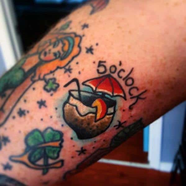 Colorful traditional-style tattoo of a coconut drink with straw, umbrella, fruit slice, and "5 o'clock" text, surrounded by stars.