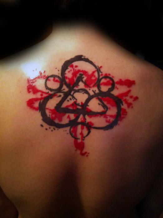Large Keywork tattoo on the upper back with bold black lines and vivid red splashes, creating a striking Coheed and Cambria-inspired design.