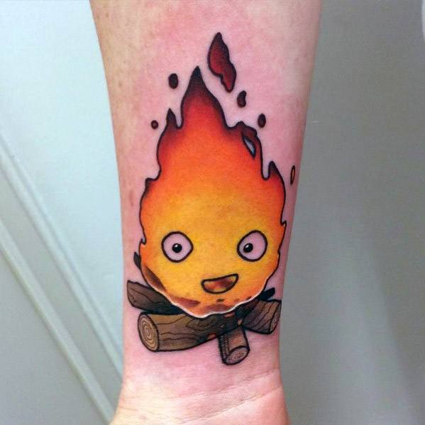 Bright and cheerful Calcifer tattoo with glowing orange flames, perched on detailed wooden logs, smiling with wide open eyes.