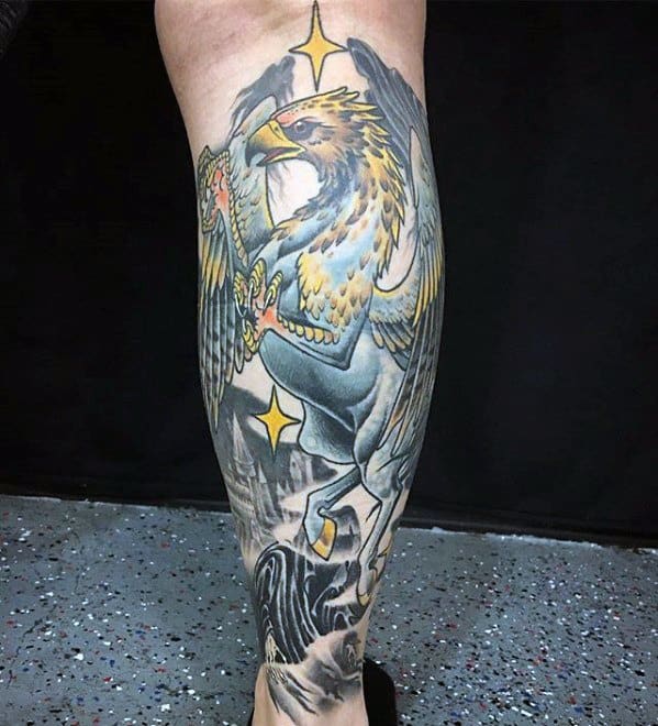 Vibrant calf tattoo of a Hippogriff attacking a Dementor, with bold yellow and blue tones and glowing magical starbursts.