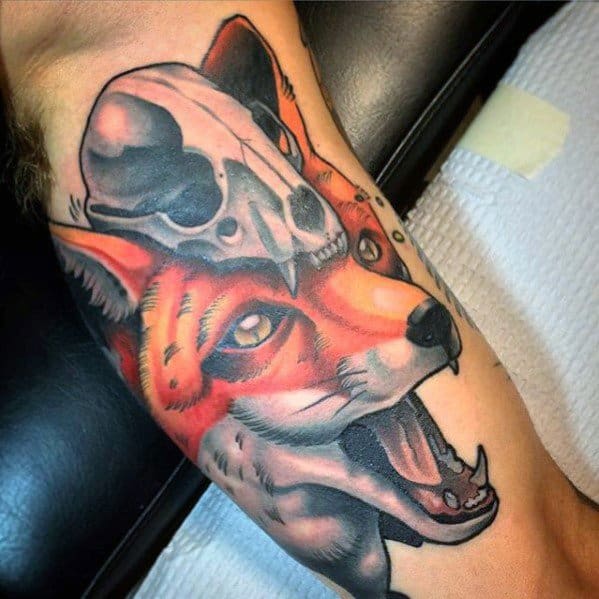 Vibrant tattoo of a snarling red fox with a skull resting on its head, done in a bold neo-traditional style.